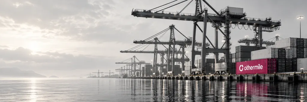 A container port at dawn with an Othermile container on the quay